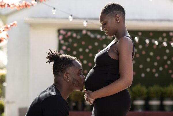 black couple, wife is pregnant and the husband is kissing his wife's stomach