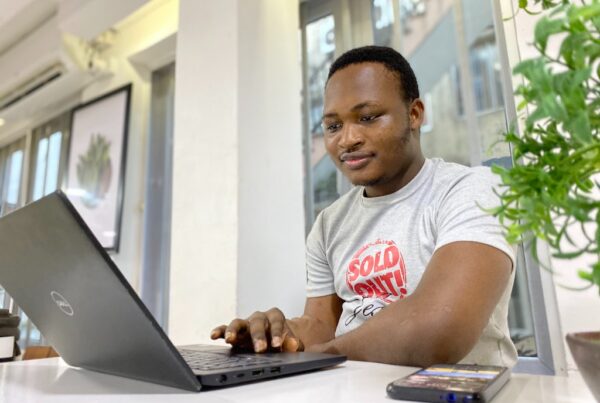 Black man smiling on laptop.