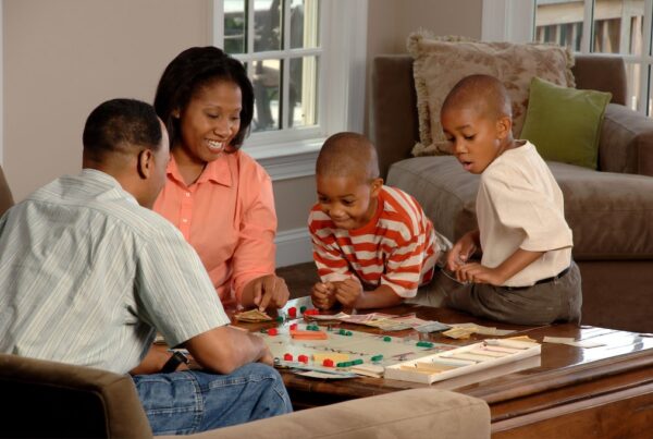 Black family playing Monopoly at the living room table.