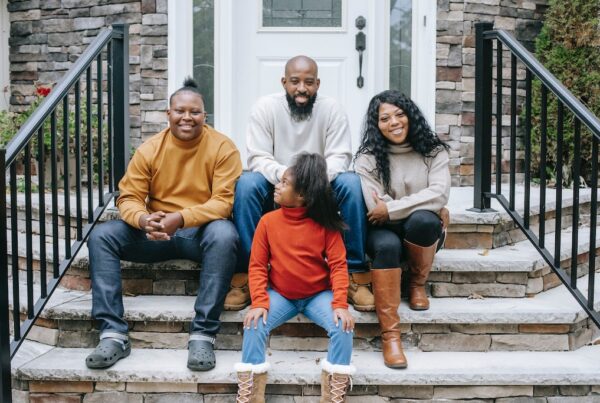 Black family sitting on porch steps.