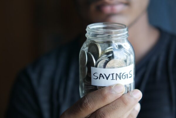 Black man holding a jar of coins that says, "Savings."