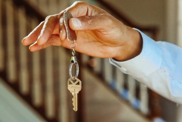 Black man's hand holding up a house key.