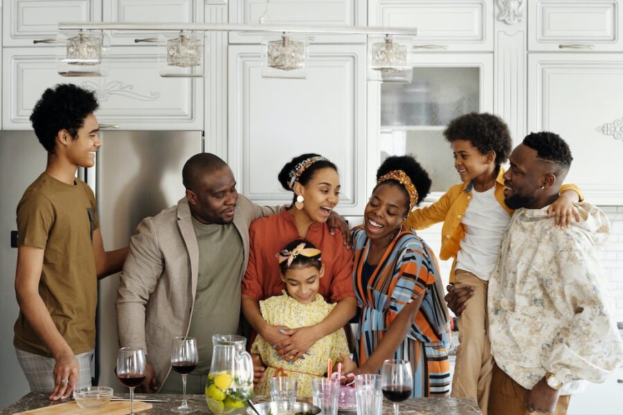 Black family in the kitchen hugging and smiling.