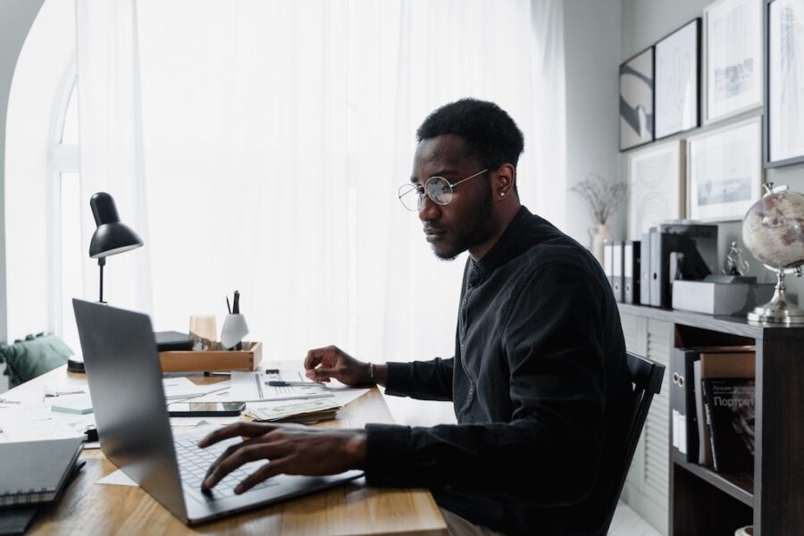 Black man on laptop sitting at a desk planning his finances.