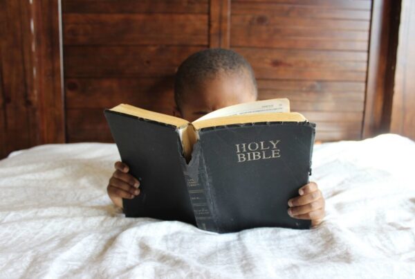a black boy lying in bed, reading a bible | Slavery Impacted Black Investors