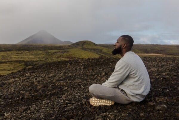 black man meditating near the mountains
