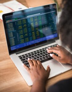 a black woman sitting at her desk typing on her lap top