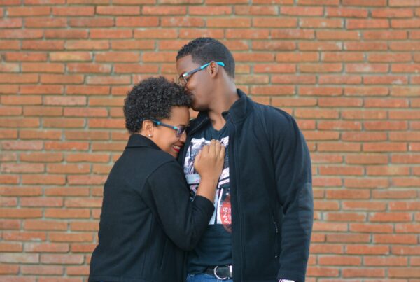 black couple in glasses, in a loving embrace | Tips To Help You Invest In Stocks with Student Loans