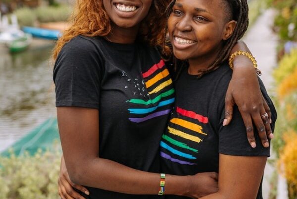 Two black lesbians half way hug with black t-shirts