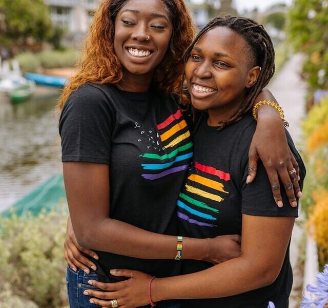 Two black lesbians half way hug with black t-shirts