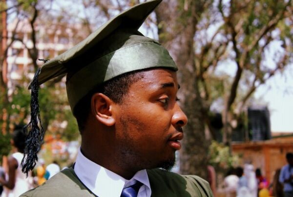 black man in green cap and gown college graduation | Navient Student Loan Forgiveness