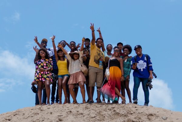 Group of black young people on a dune on the beach smiling and happy.