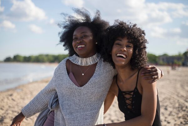 Two black women laughing at the beach.