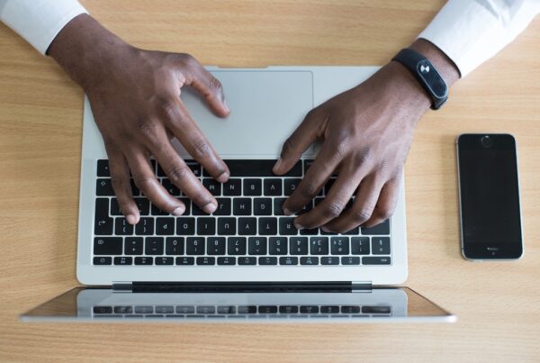 Black man typing on a laptop.