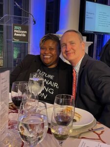 Black Woman and white man sitting down at a formal award dinner