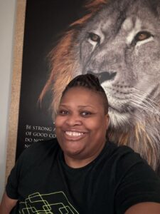 Black woman with locs smiling in a green shirt, representing financial empowerment and joy